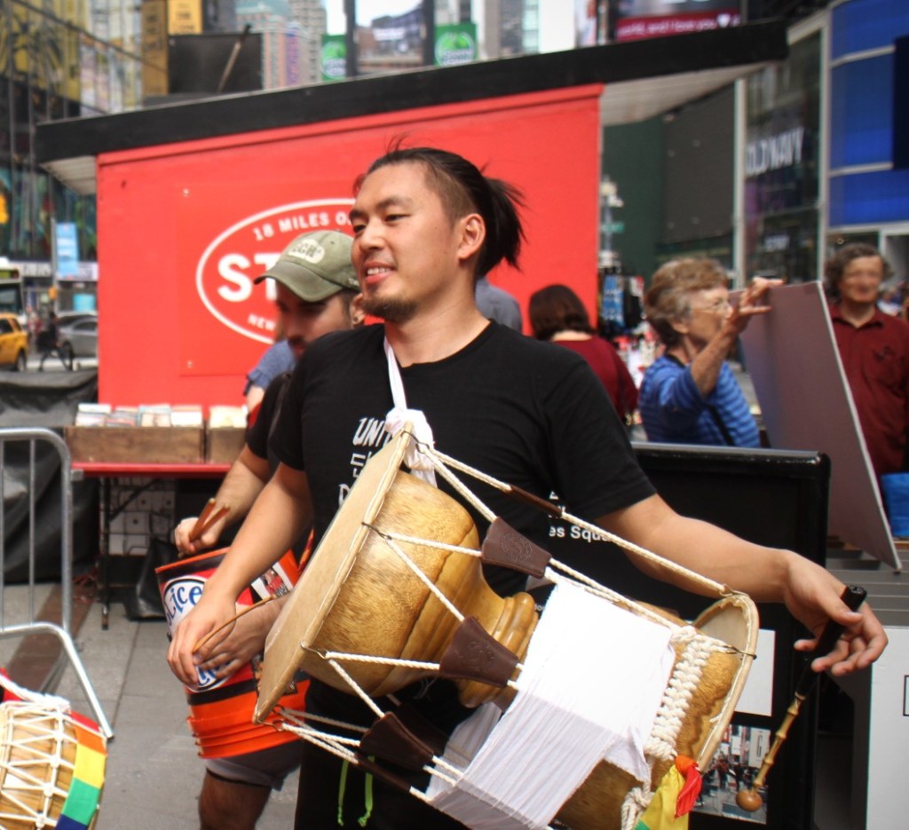 Haruki Eda, a man with a ponytail and beard, holds a traditional Korean drum.