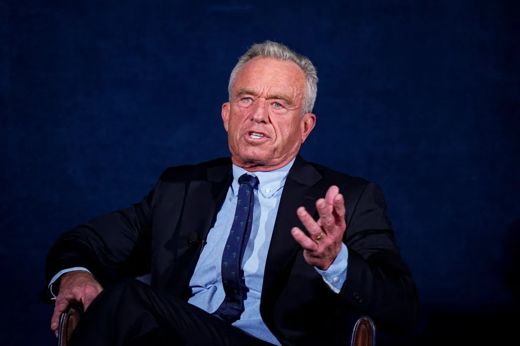 Robert F. Kennedy Jr., wearing a suit and palm tree tie, speaks with an open hand gesture.