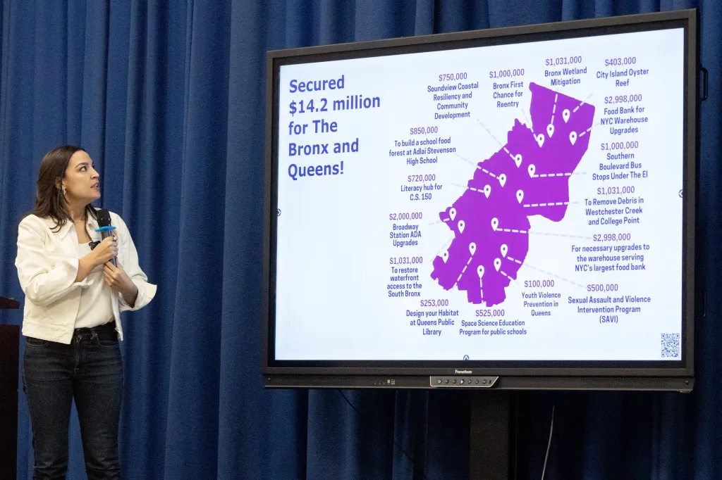 Rep. Alexandria Ocasio-Cortez presents a map of the Bronx and Queens highlighting $14.2 million in secured funding for various projects.