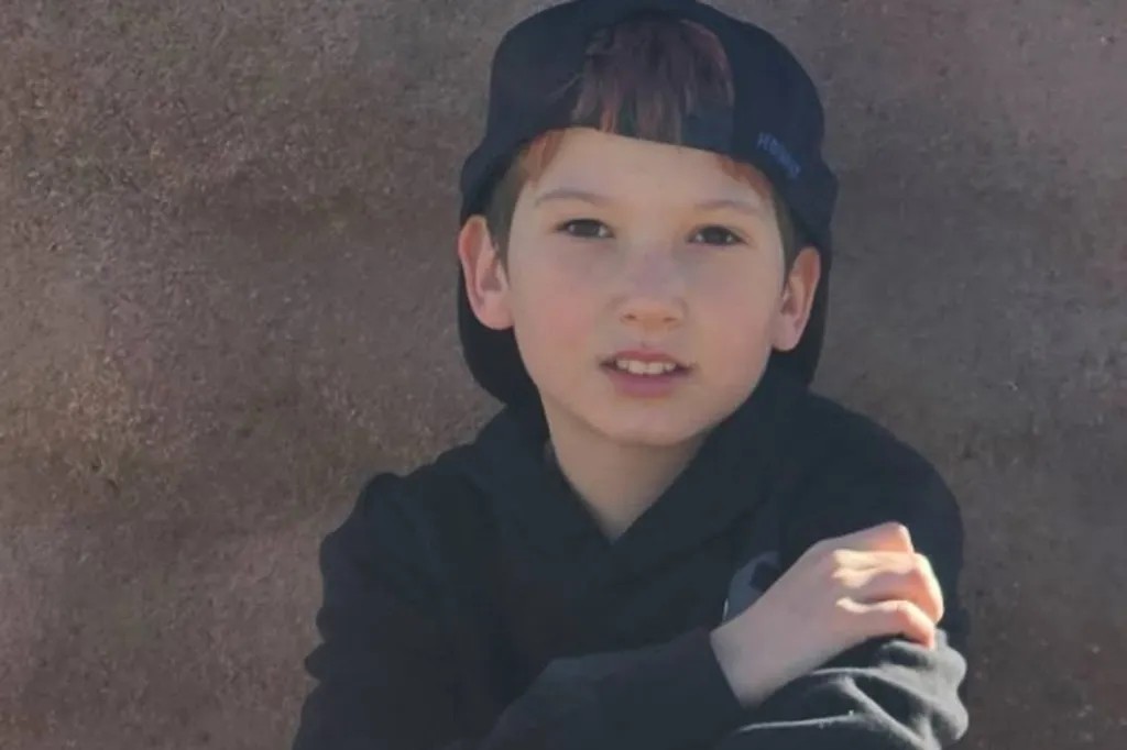 Talon Whinery, a young boy with reddish-brown hair, wearing a black cap and hoodie.