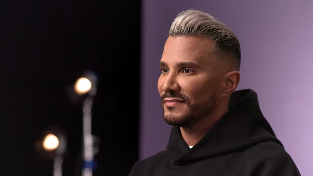 Jay Manuel in a black hoodie with a gray and white hairstyle and beard.