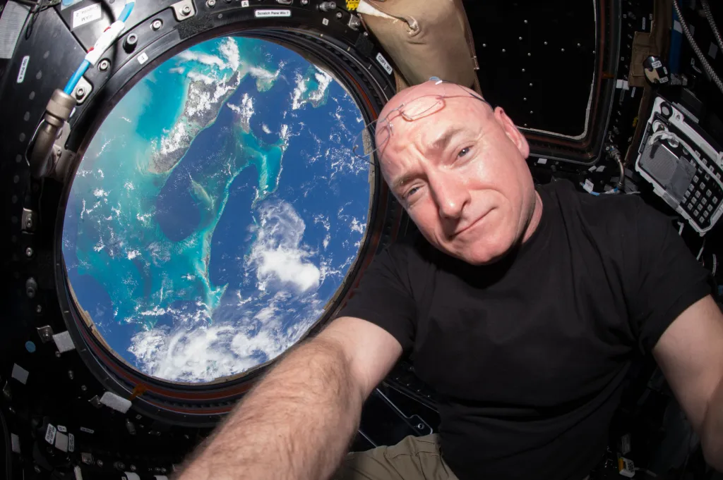Astronaut Scott Kelly floating in the Cupola module of the International Space Station with Earth visible through the window.