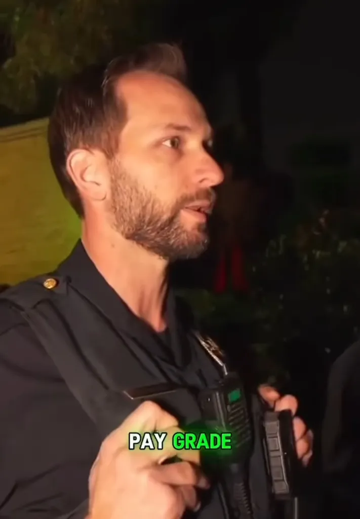 A police officer with a beard and dark uniform talks at night, holding a radio with text overlay 