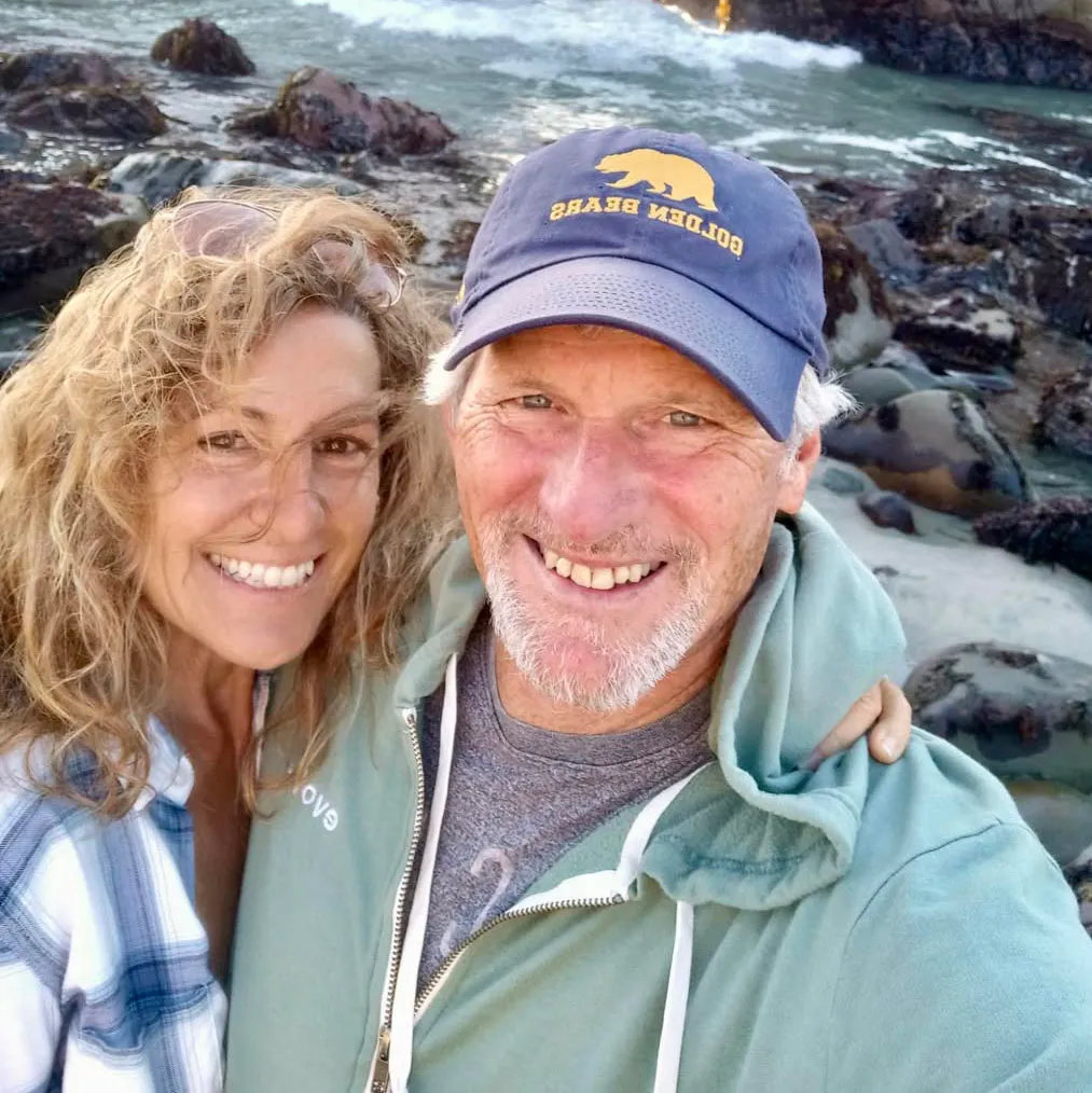 Beth and Jim Hamilton smiling by the ocean.