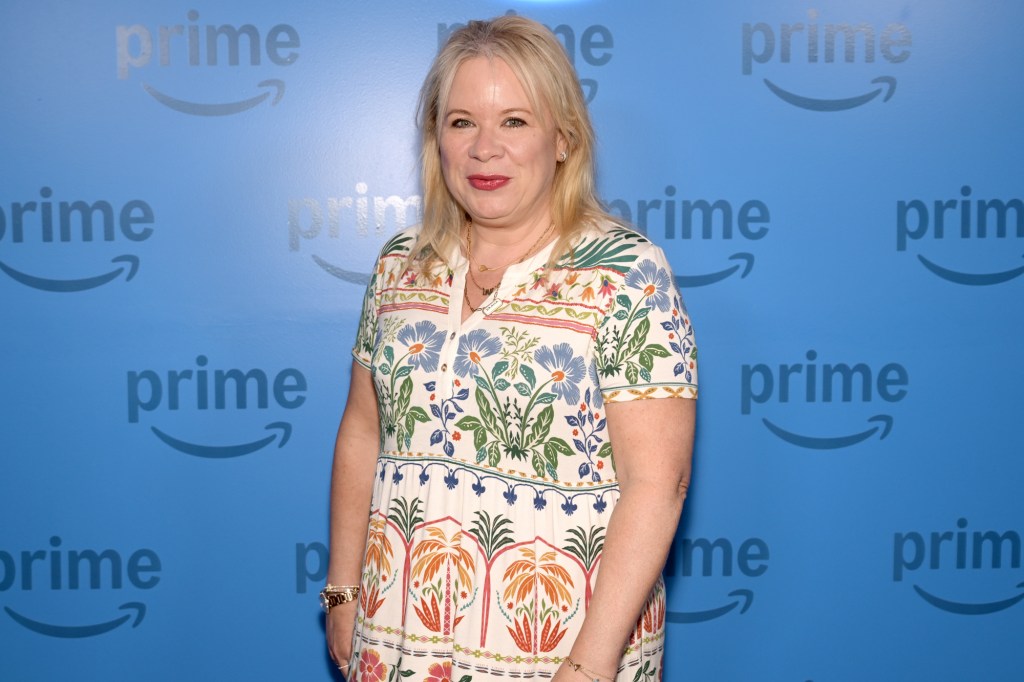 Julie Plec posing in front of a blue Prime Video backdrop.