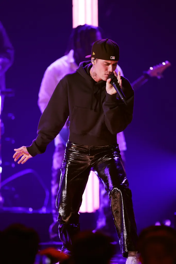 Justin Bieber performing onstage, singing into a microphone with his eyes closed.