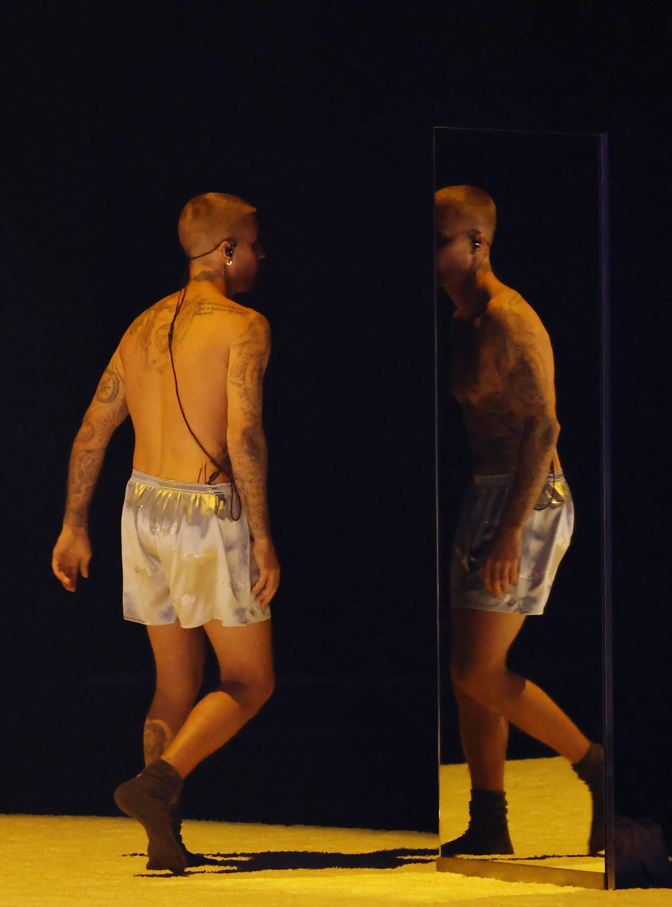 Justin Bieber, shirtless and in boxer shorts, walking away from the camera on a stage at the Grammy Awards.
