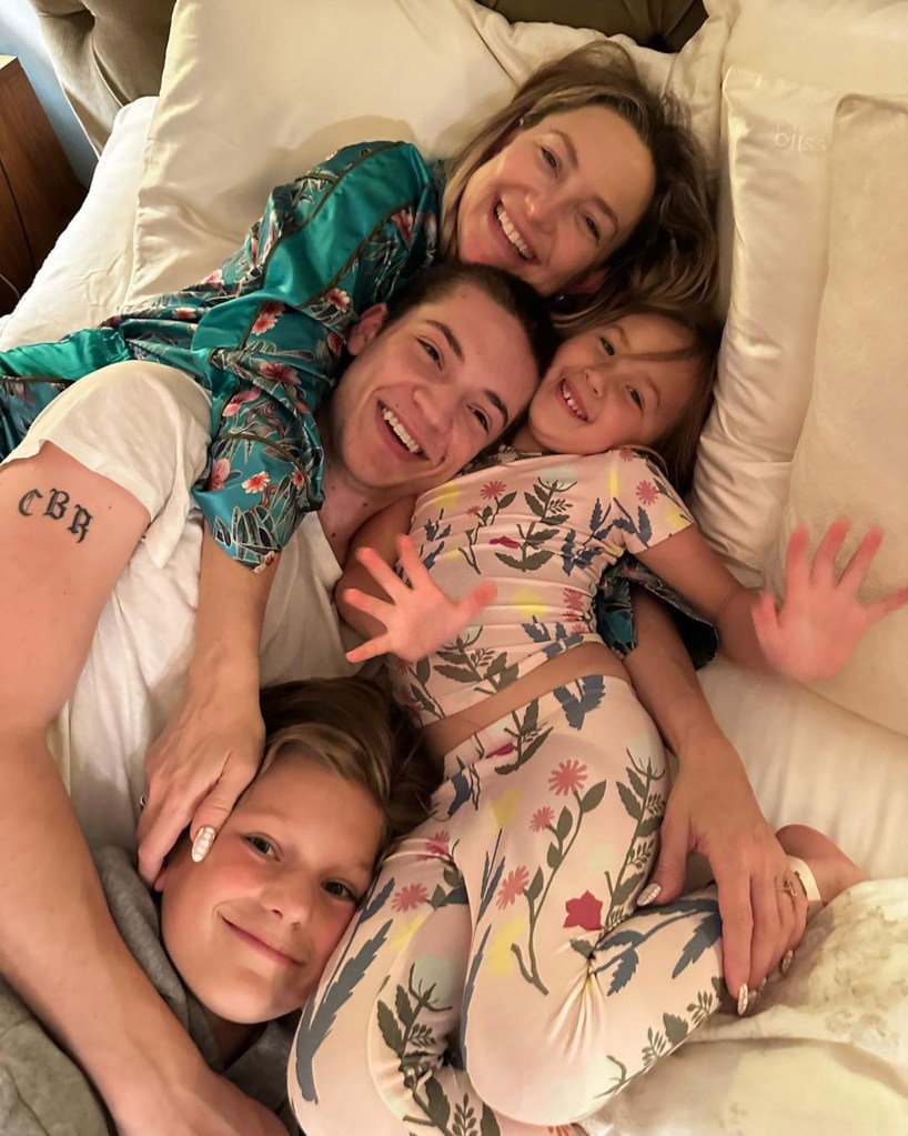Kate Hudson and Elle Evans smiling with two children on a bed.