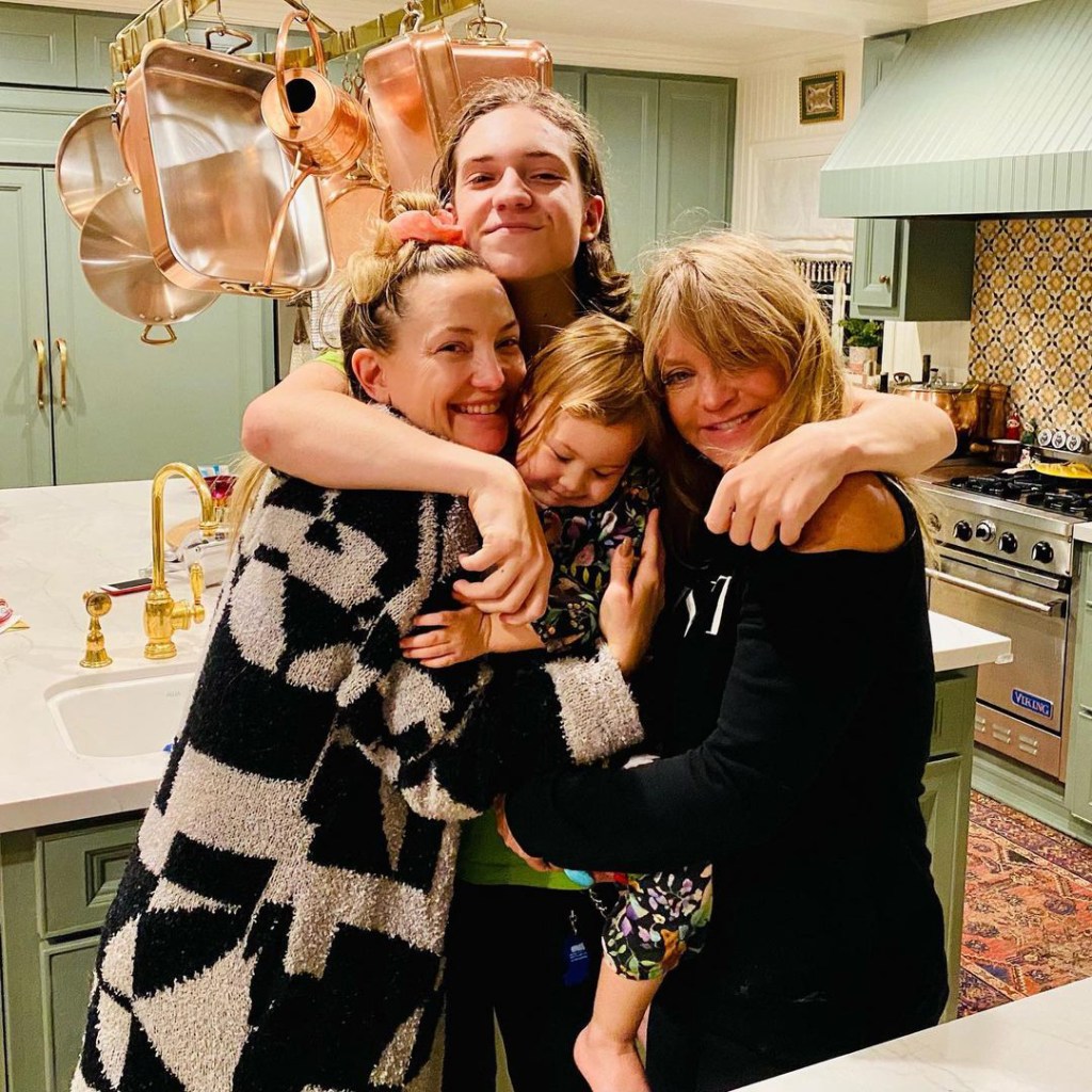 Kate Hudson and Goldie Hawn with two other family members in a group hug.