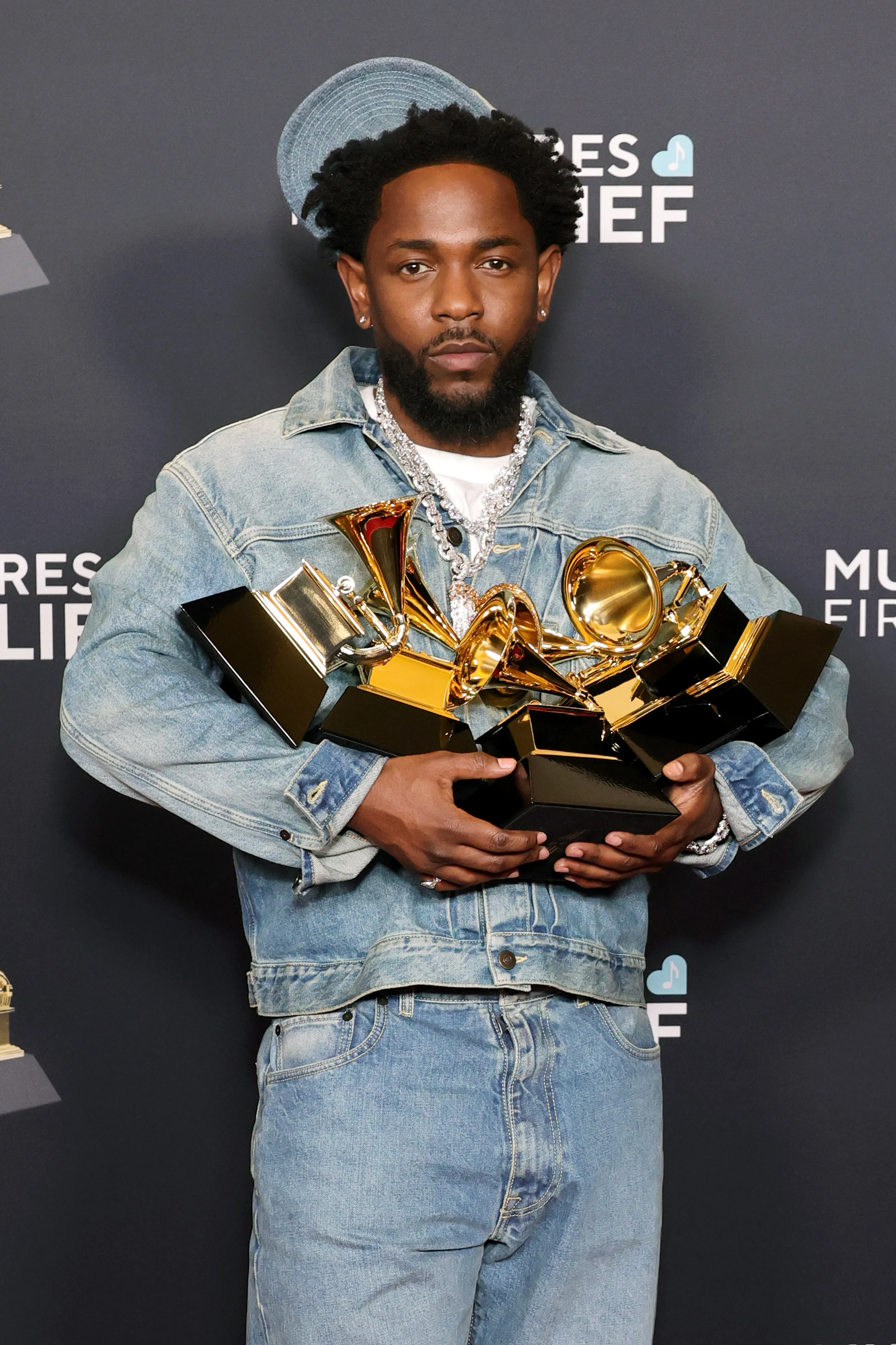 Kendrick Lamar holding multiple Grammy awards.