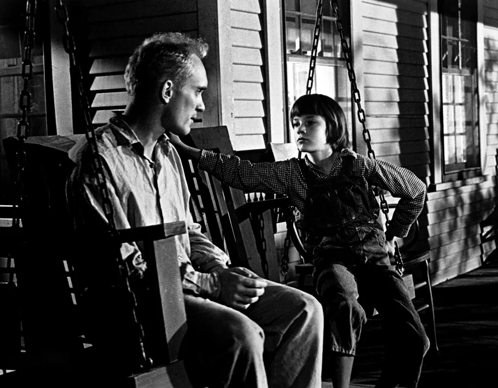 Robert Duvall and Mary Badham on a porch swing.