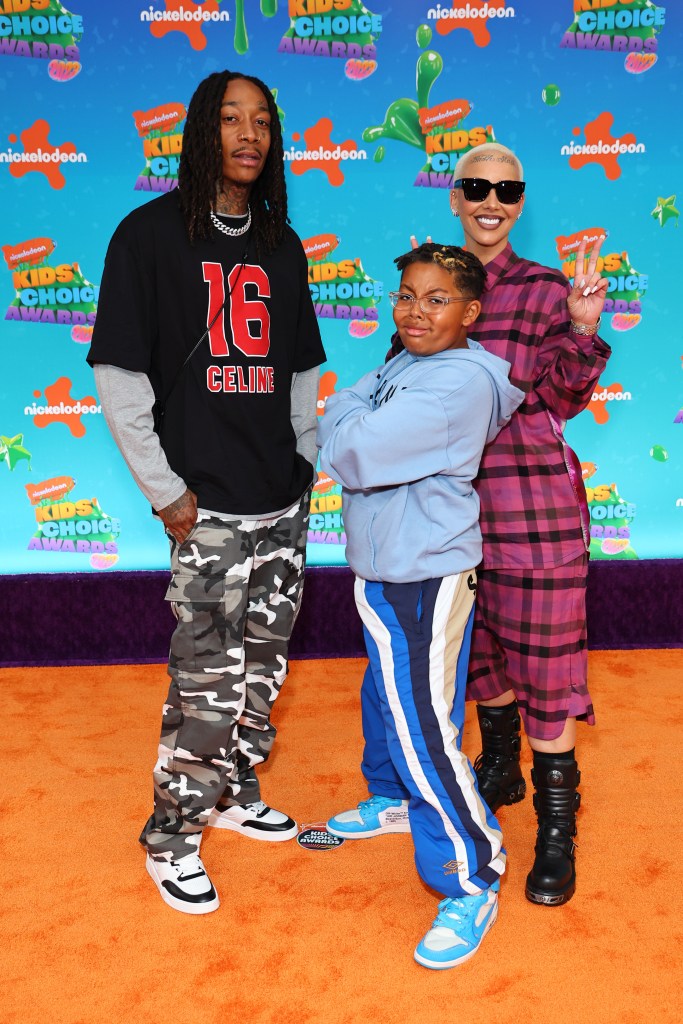 Wiz Khalifa, Sebastian Taylor Thomaz, and Amber Rose posing for a photo on the orange carpet at the 2023 Nickelodeon Kids' Choice Awards.