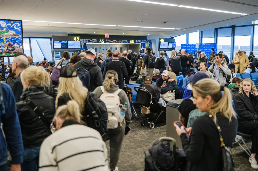 People waiting in a crowded airport terminal due to flight delays and cancellations.