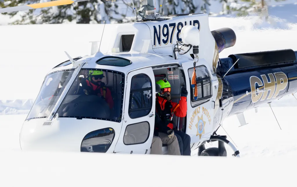 California Highway Patrol helicopter in the snow with two crew members inside.