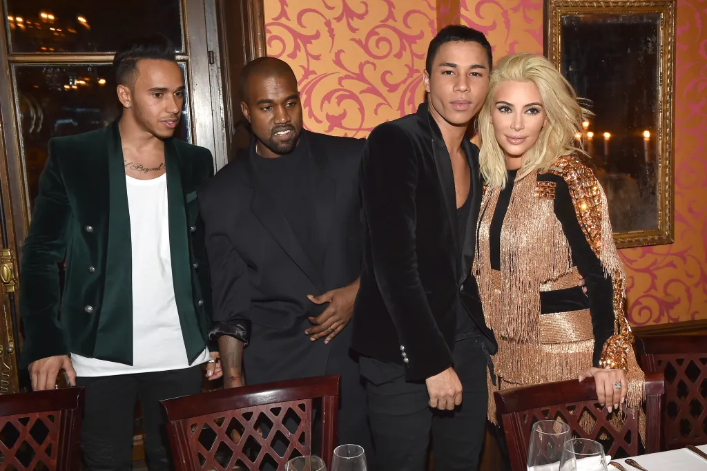 Lewis Hamilton, Kanye West, Olivier Rousteing, and Kim Kardashian pose together at a dinner.