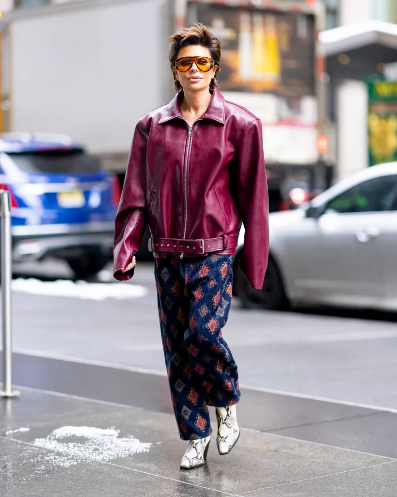 Lisa Rinna wearing a burgundy leather bomber jacket, patterned pants, and snakeskin boots.