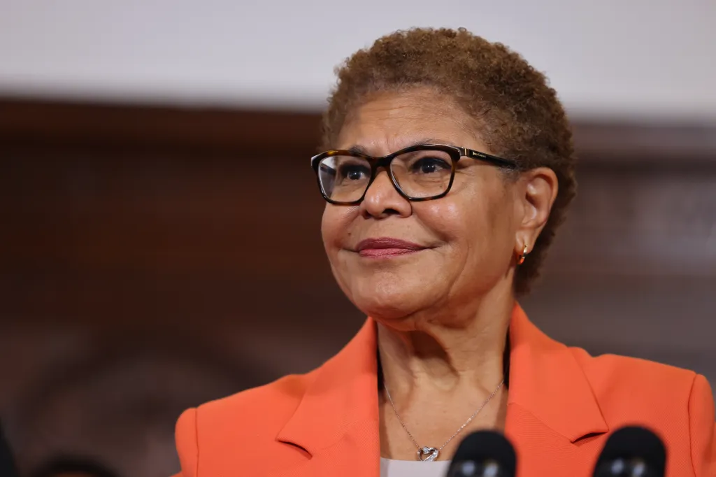 Los Angeles Mayor Karen Bass in an orange blazer and glasses, speaking at an event.