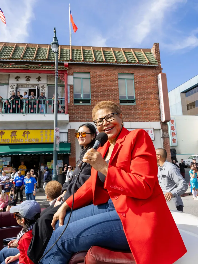 Los Angeles Mayor Karen Bass speaking into a microphone at the Golden Dragon Parade.