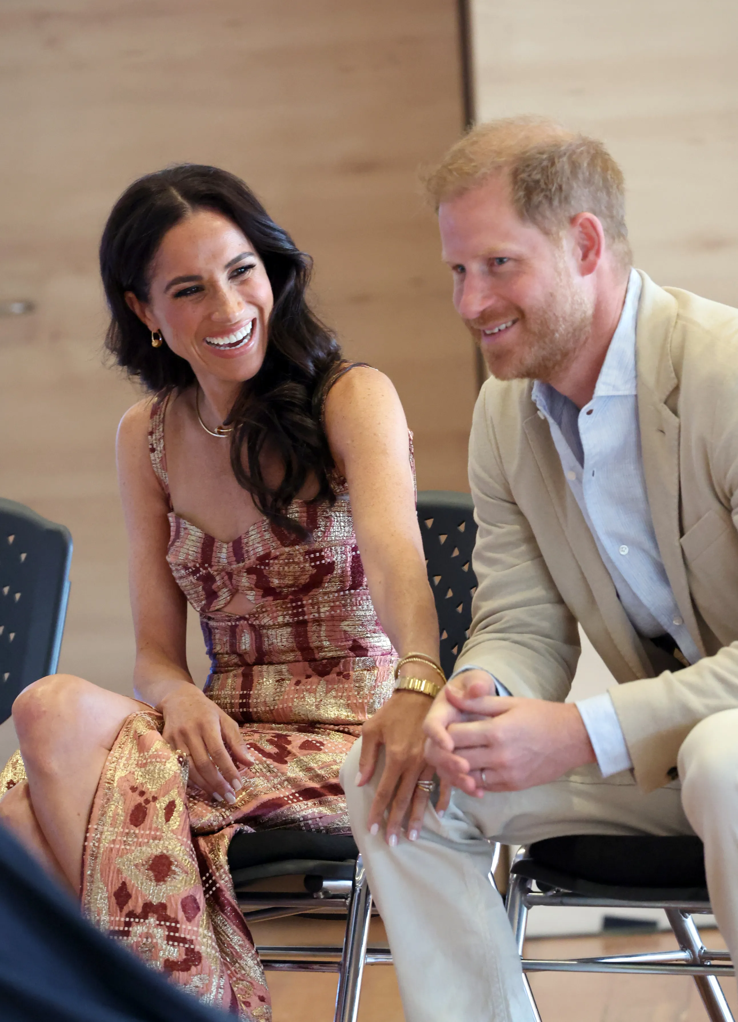 Meghan, Duchess of Sussex, and Prince Harry, Duke of Sussex, smiling and laughing together while seated during their Colombia visit.