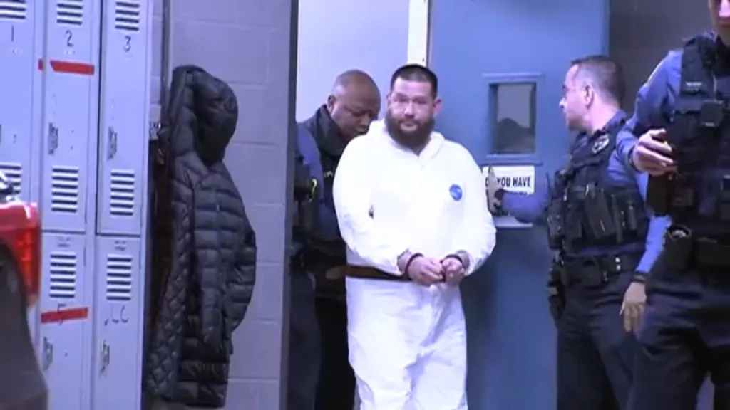Michael Phillips in handcuffs, escorted by police.