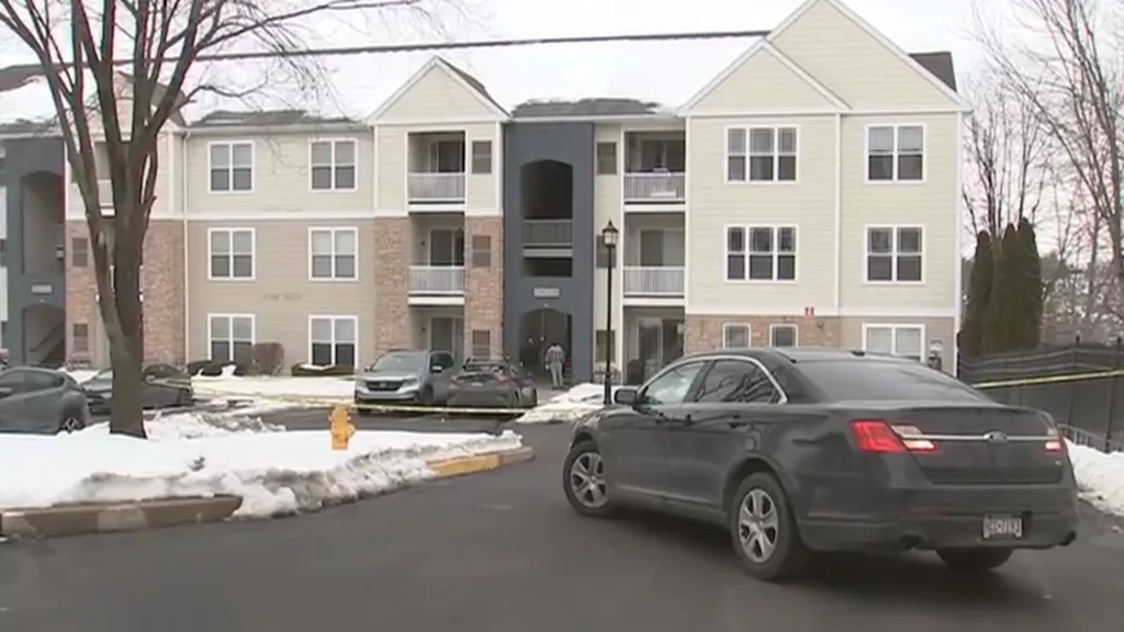 Apartment building with snow on the ground and yellow police tape.