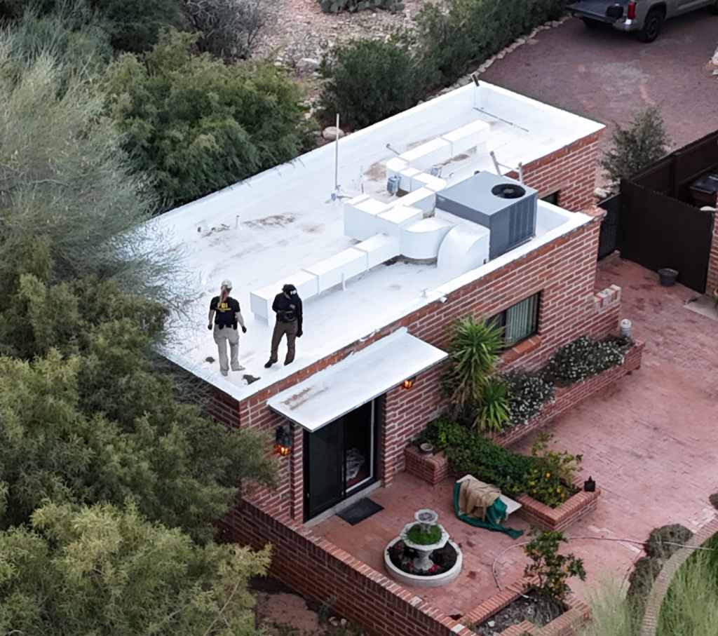 Aerial view of two FBI officers on the roof of Nancy Guthrie's brick house in Tucson, AZ.