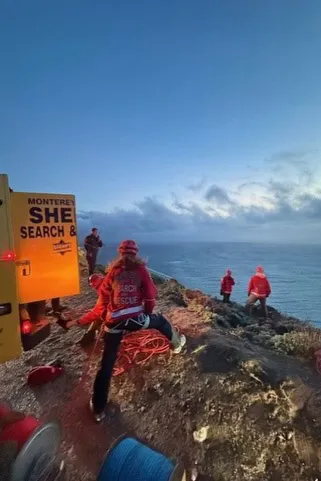 Monterey County Search and Rescue team assisting in recovery efforts on a cliffside by the ocean.