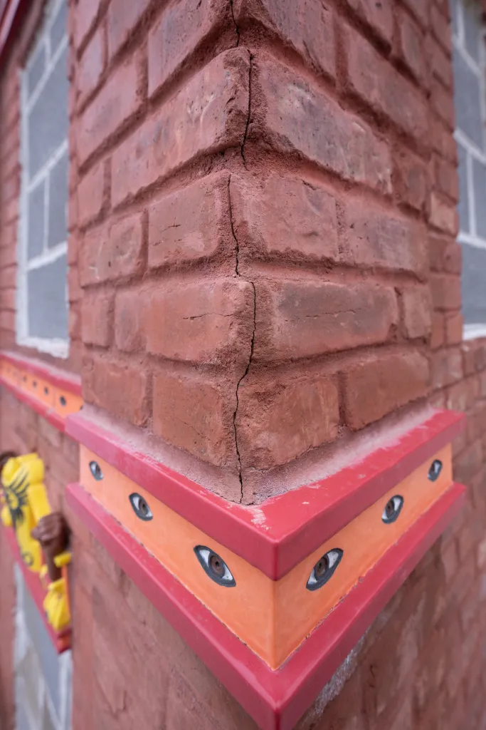 Close-up of a brick sculpture showing cracks and decorative eyes.