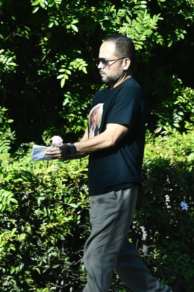 A mourner leaves a card and flower on the doorstep of Catherine O'Hara's home.