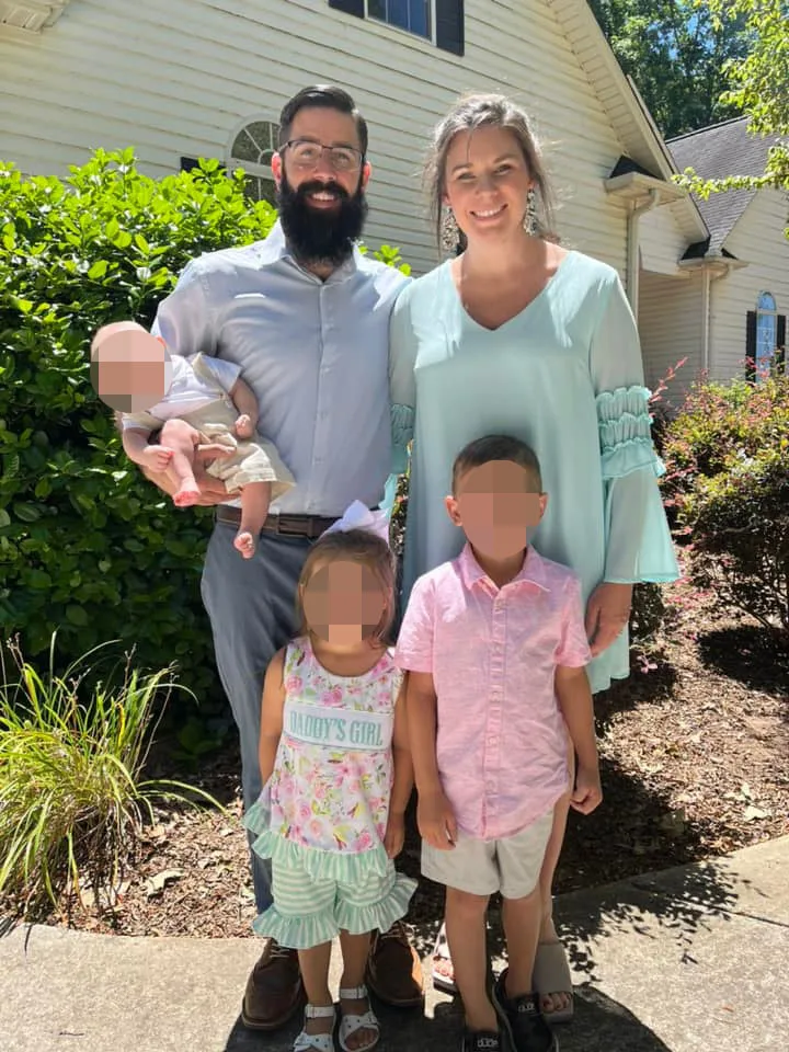 A family of five posing for a picture in front of a house.