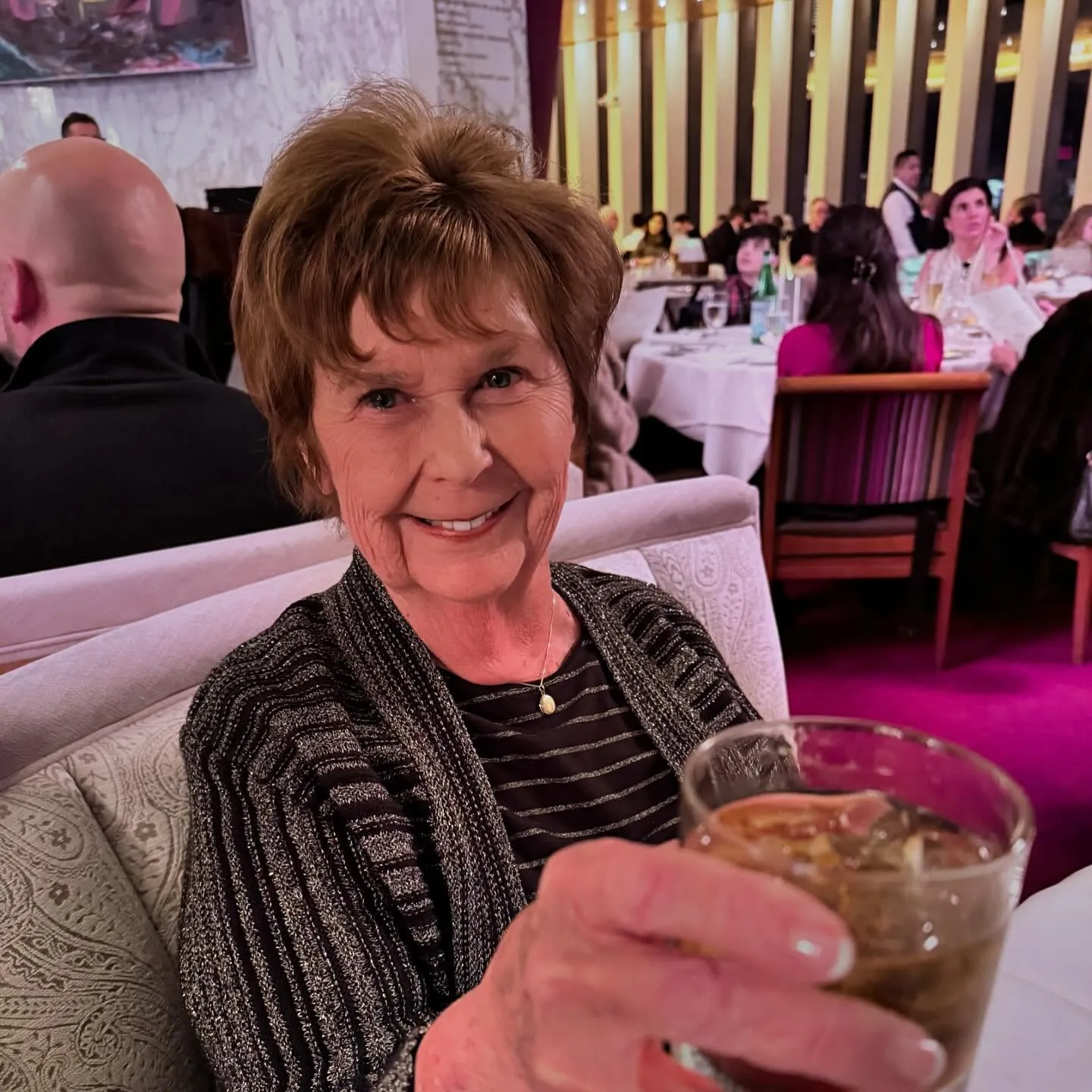 Nancy Gunthrie smiling and holding a drink in a restaurant.