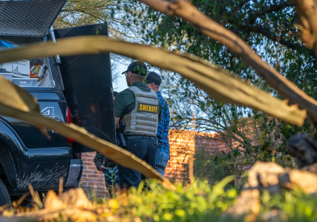 A sheriff's deputy stands by the back of a truck with forensic supplies during an investigation.