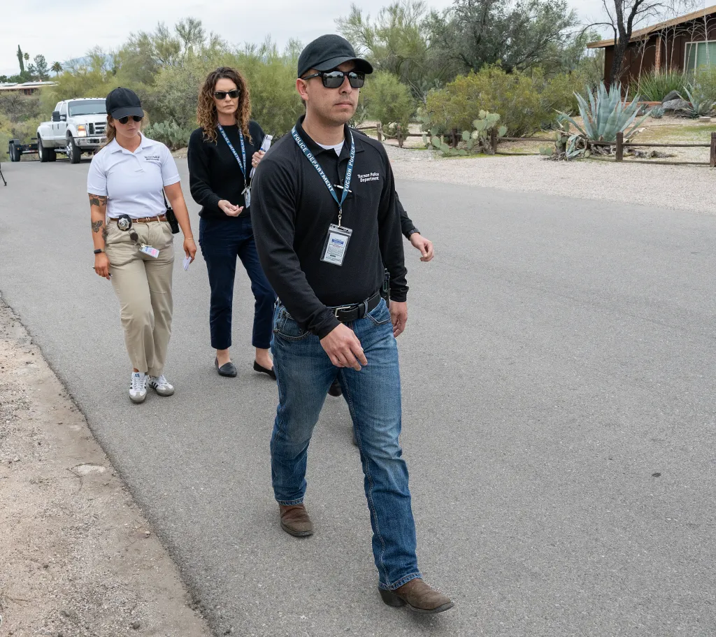 Three Tucson Police Department investigators canvassing a neighborhood.