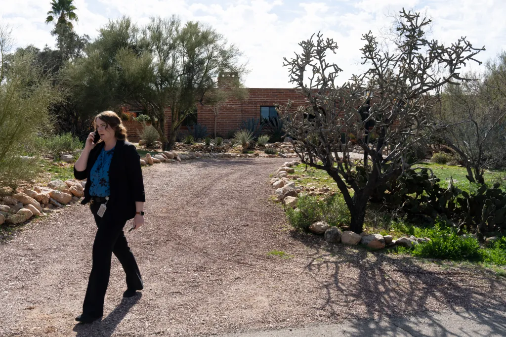 Nancy Guthrie's house in Tucson, Arizona, with a woman walking by on the phone.