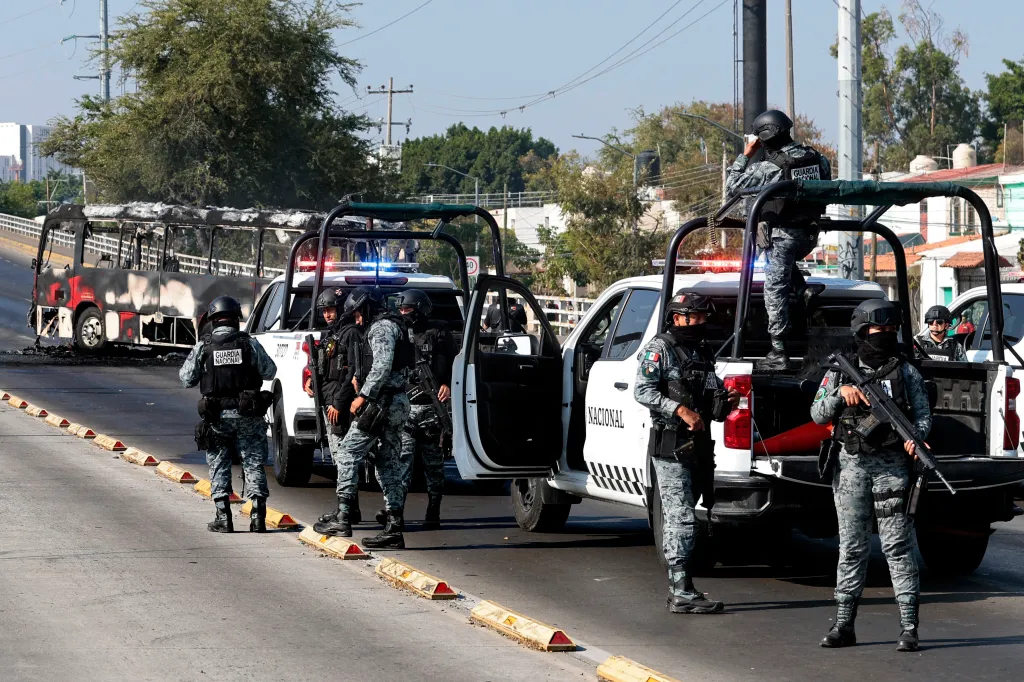 Mexican National Guard members stand guard near a burnt bus following an operation in Jalisco.