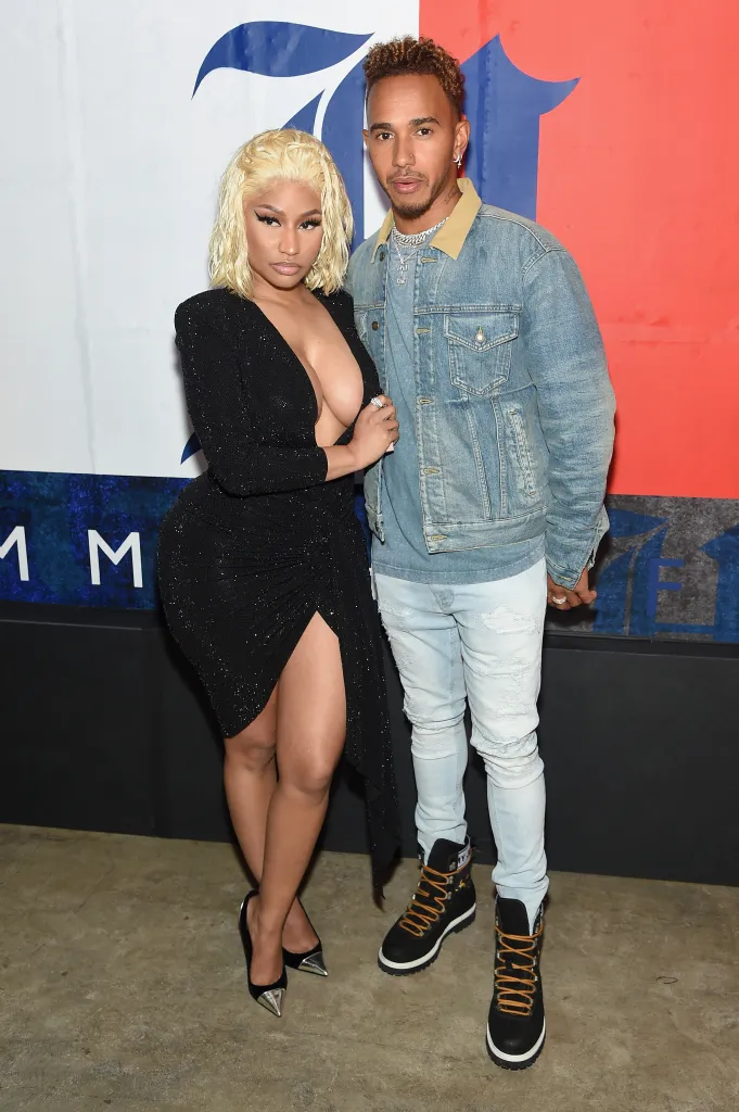 Nicki Minaj in a black dress and Lewis Hamilton in a denim jacket and light-wash jeans posing together.