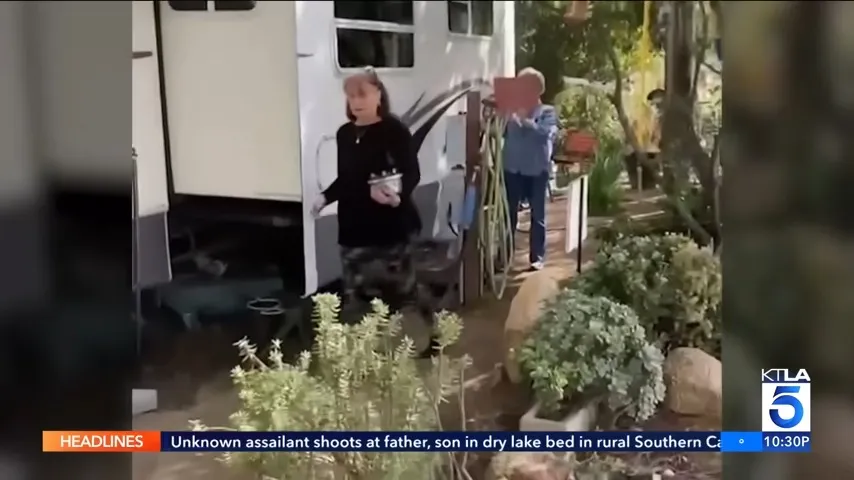 Two residents exiting a white RV, with one carrying a red object.