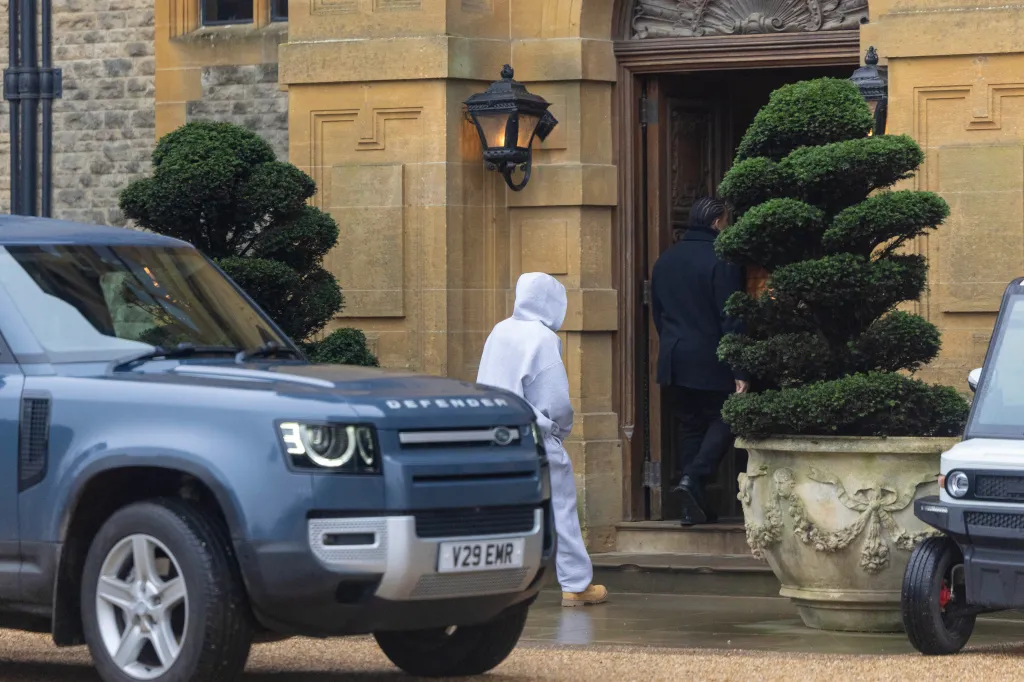 Kim Kardashian wearing a grey tracksuit entering a building with Lewis Hamilton.