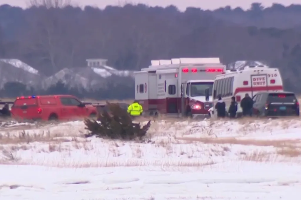 Emergency vehicles and personnel on a snow-covered field.