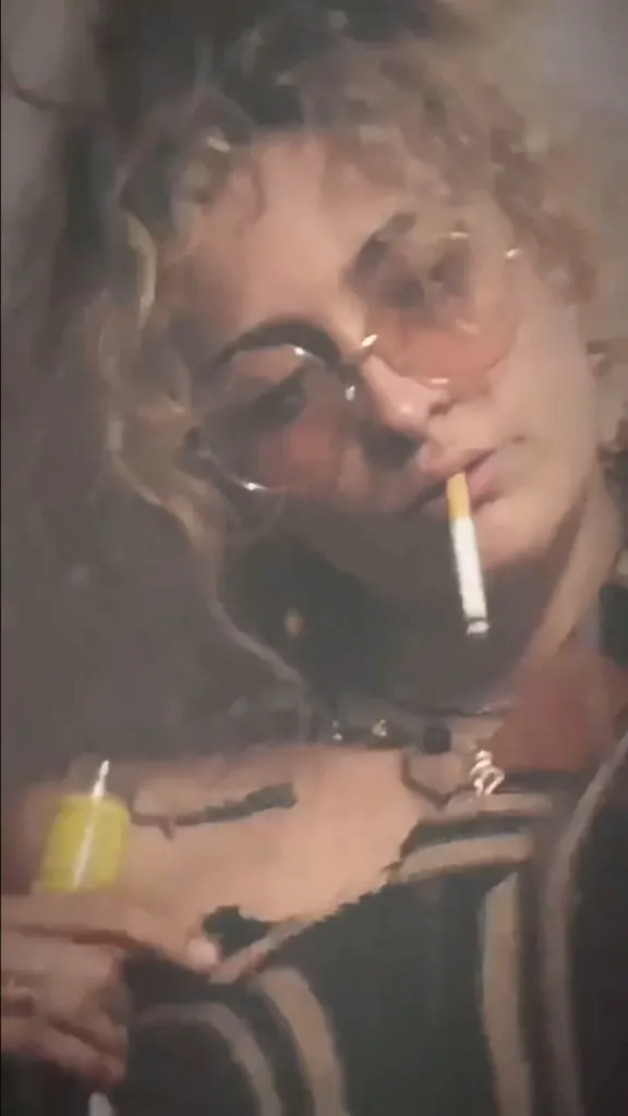 Paris Jackson wearing sunglasses and smoking a cigarette.