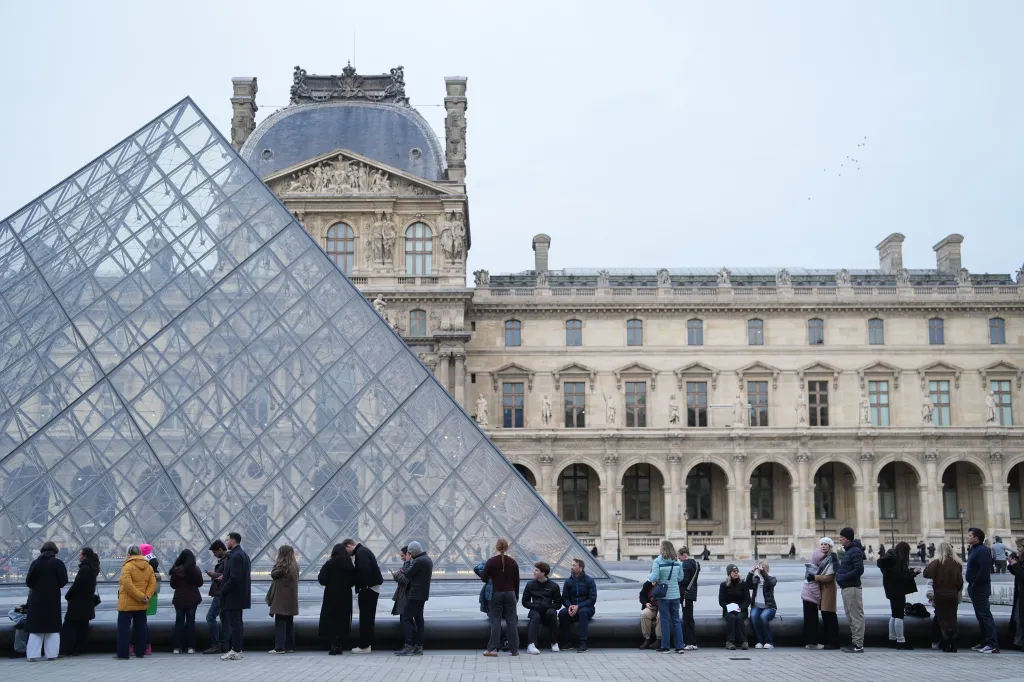 People wait outside the Louvre Museum in Paris.