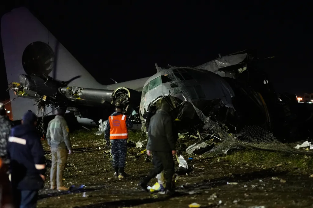 People walk among the wreckage of a crashed plane at night in El Alto, Bolivia.