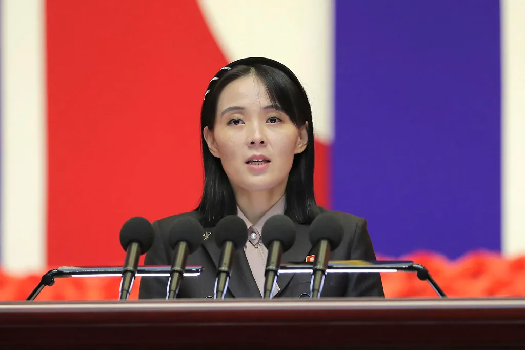 Kim Yo Jong speaking at a podium with microphones during a national meeting against the coronavirus.