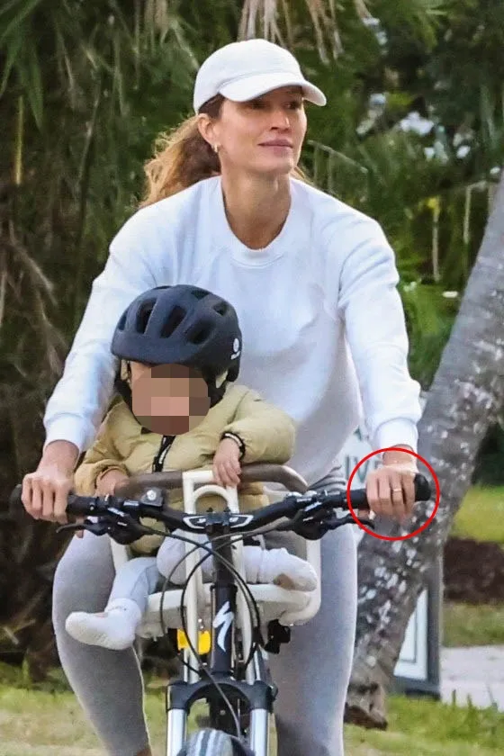 Gisele Bundchen riding a bicycle with her son, wearing a wedding band.