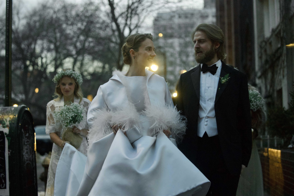 Maya Hawke and Christian Lee Hutson smiling and walking together in their wedding attire.