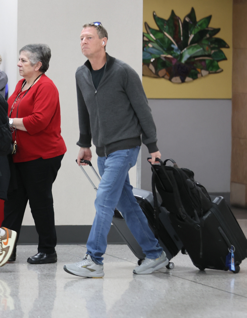 Michael Feldman walking through an airport with luggage.