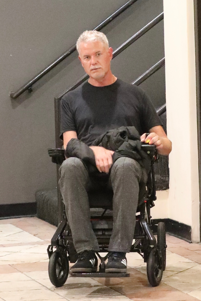 Eric Dane in a wheelchair holding a black coat on his lap.
