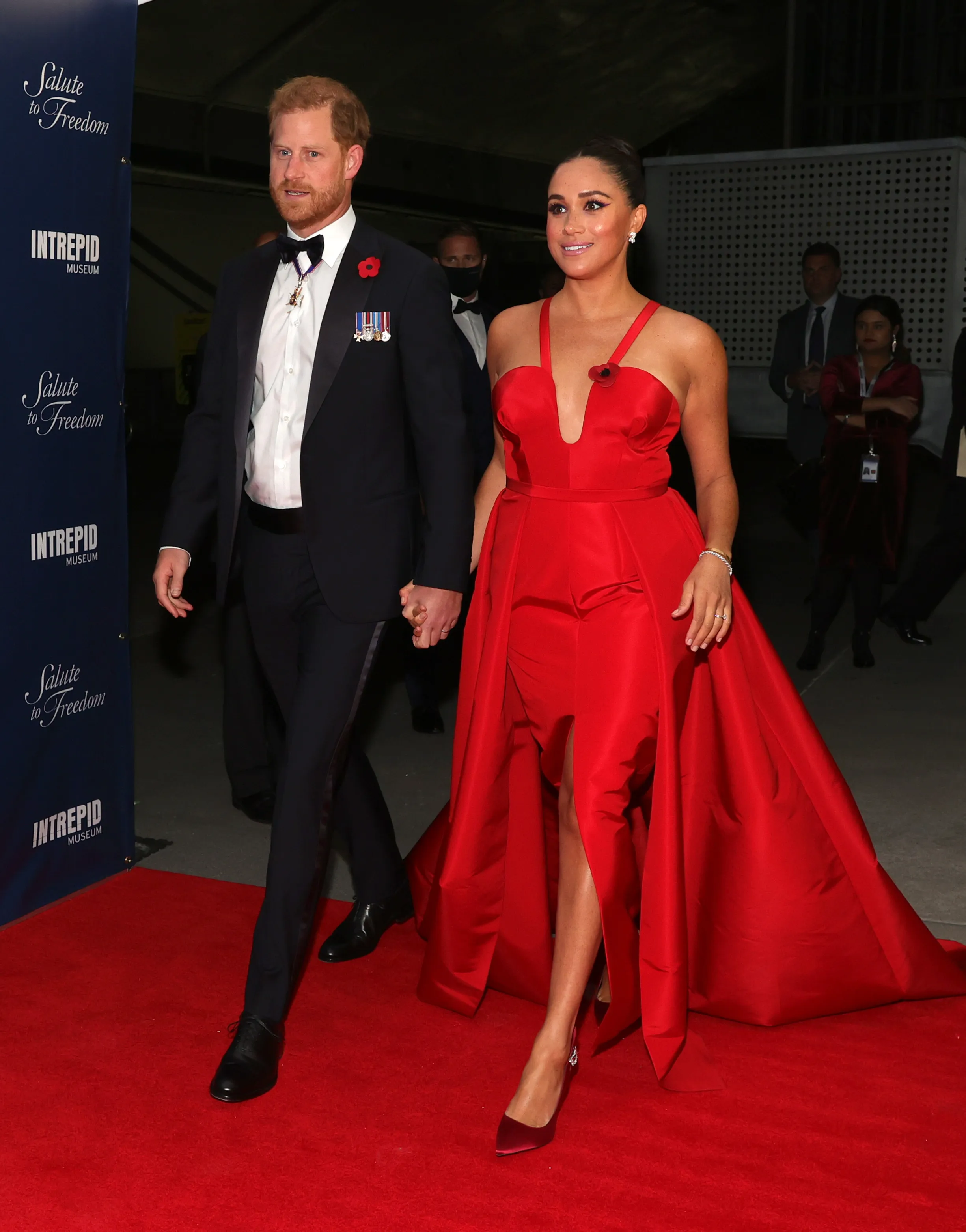 Prince Harry and Meghan Markle holding hands on a red carpet at the 2021 Salute to Freedom Gala.