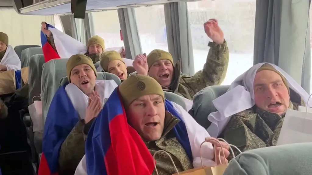 Russian prisoners of war in a bus celebrating their release with Russian flags.