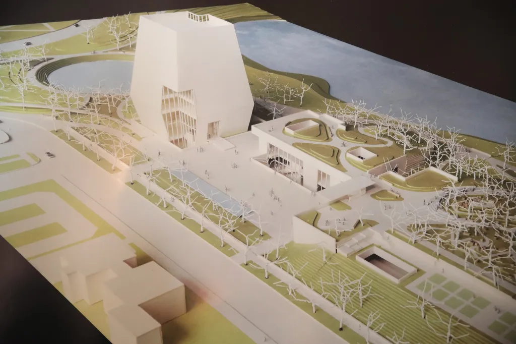 Illustration of the proposed Obama Presidential Center, including a tall, white museum building, a library, and a forum building, surrounded by green landscaping and bare trees.